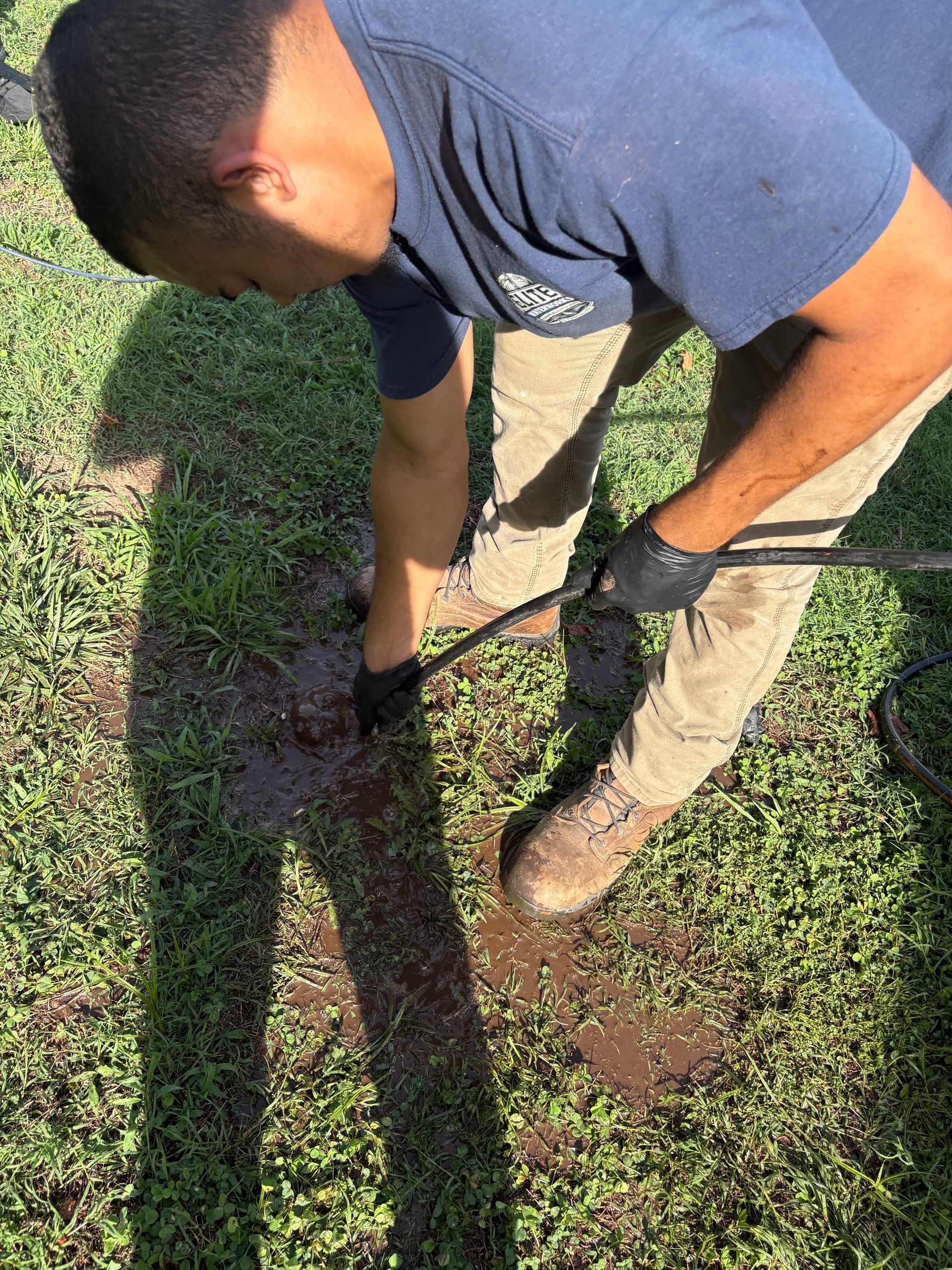 Person using a shovel to dig a hole in a grassy yard