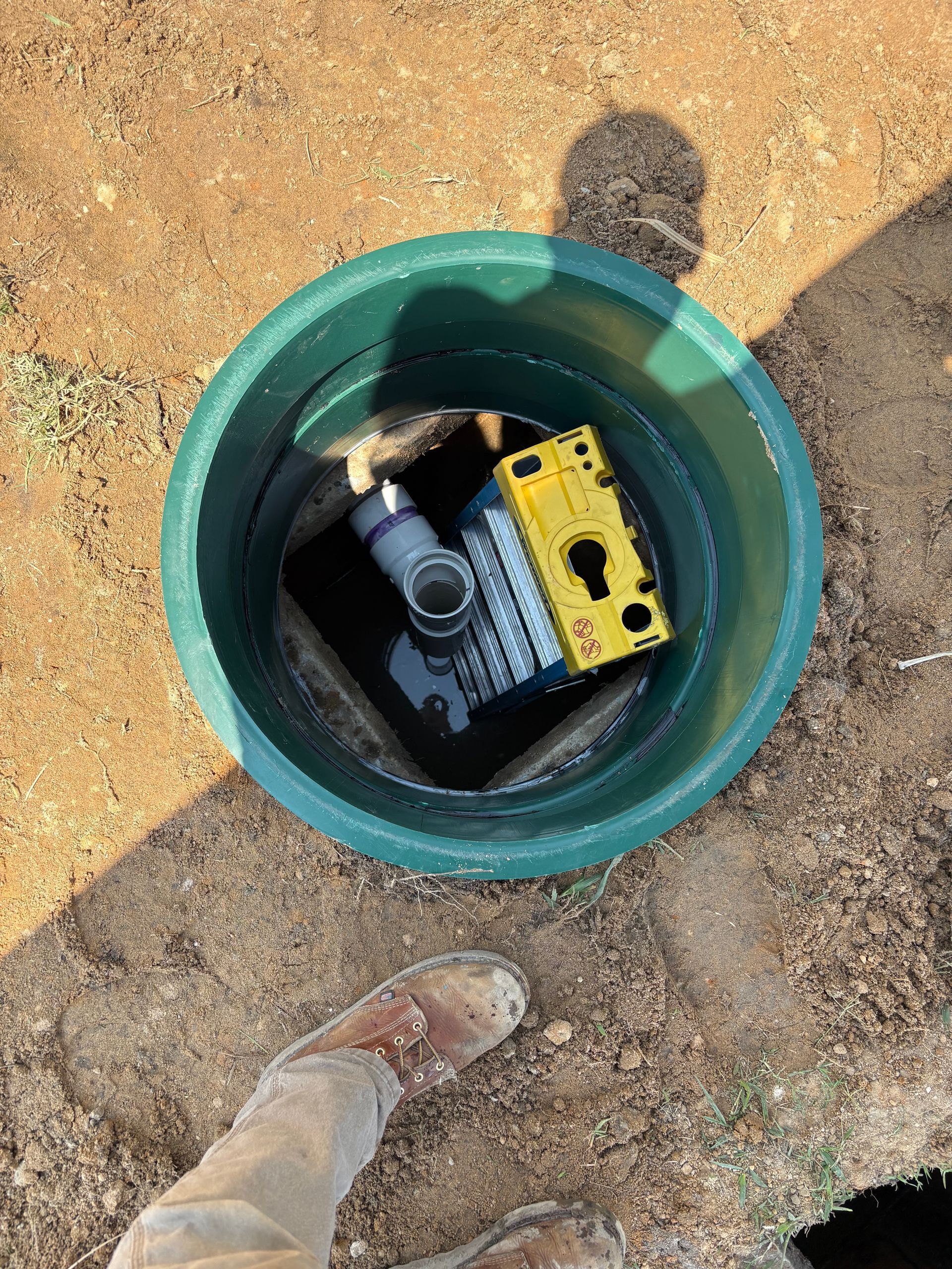 Open green utility box in dirt with a black and yellow device inside