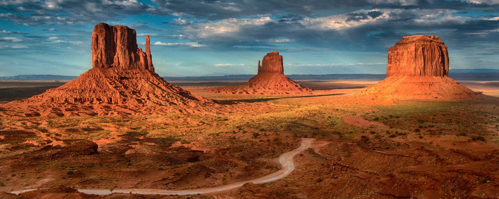 A desert landscape with mountains and a road in the foreground.