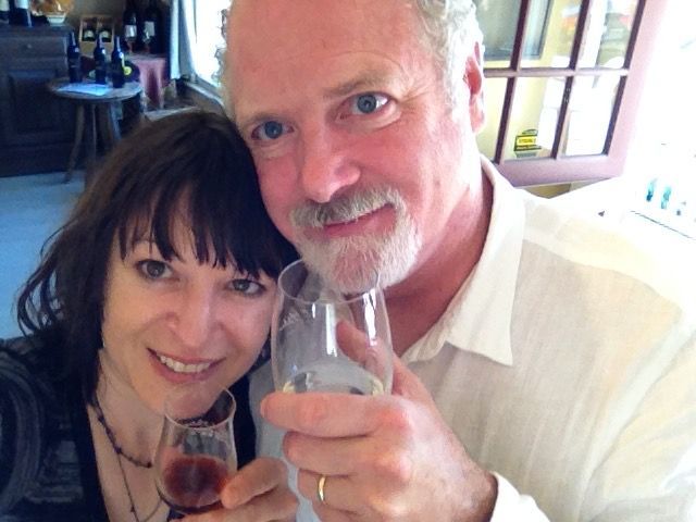 Woman and man smiling, holding wine glasses, indoors.