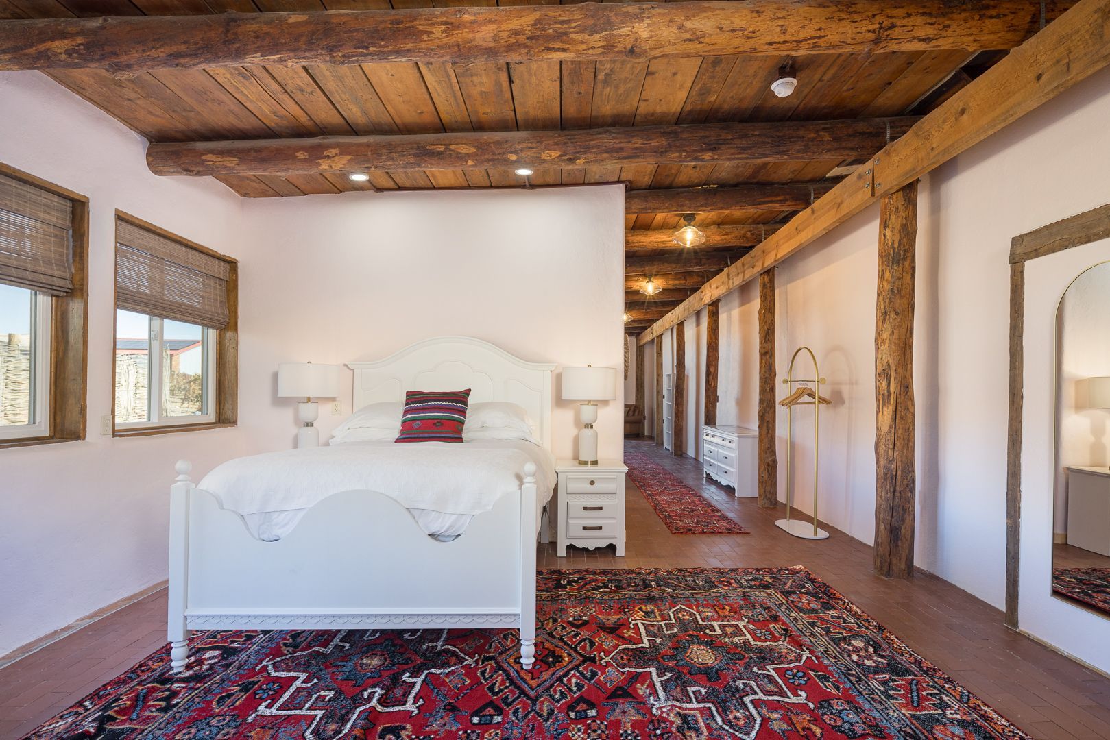 A bedroom with a white bed and a red rug.