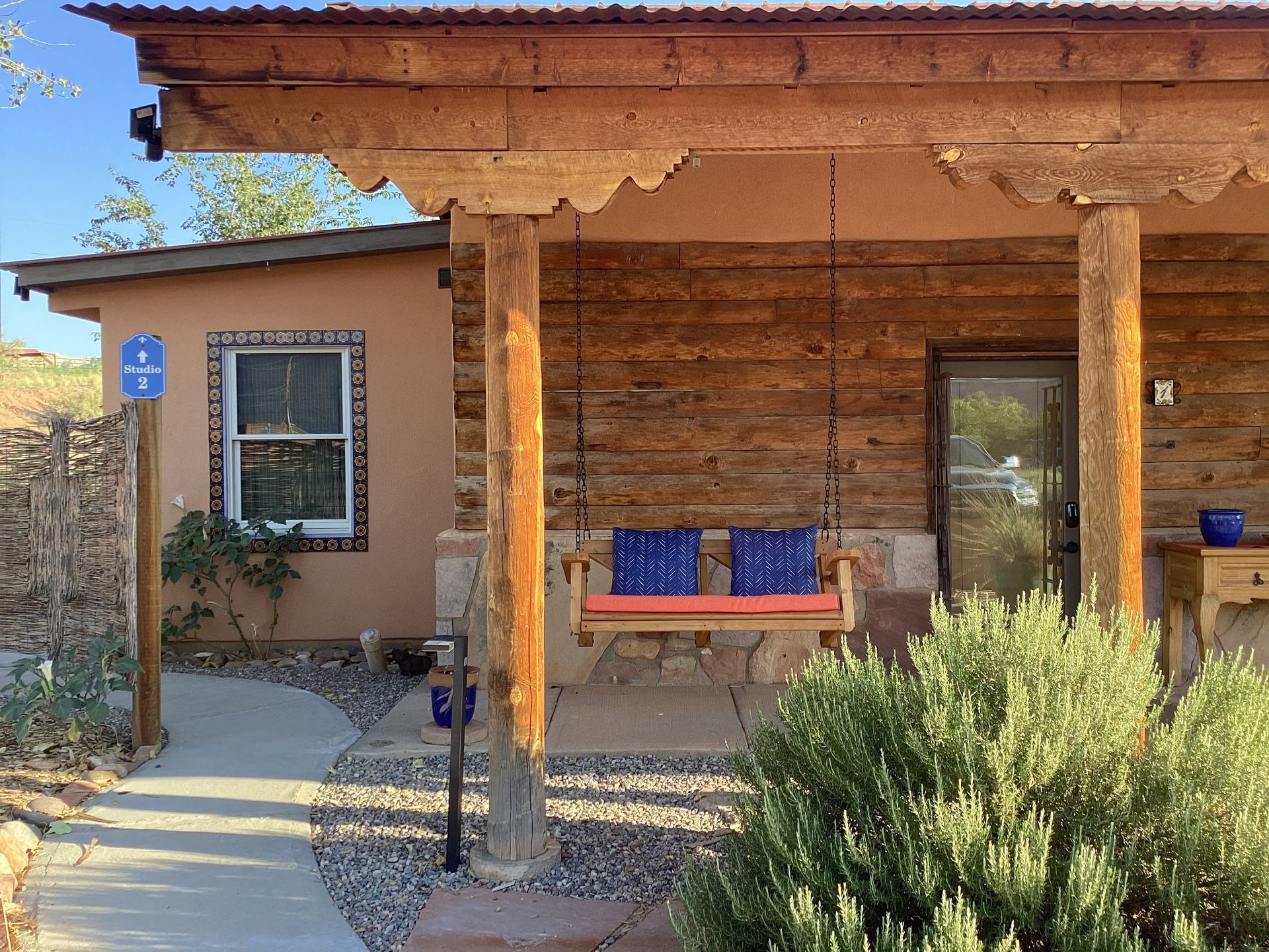 A wooden porch with a swing and a blue sign