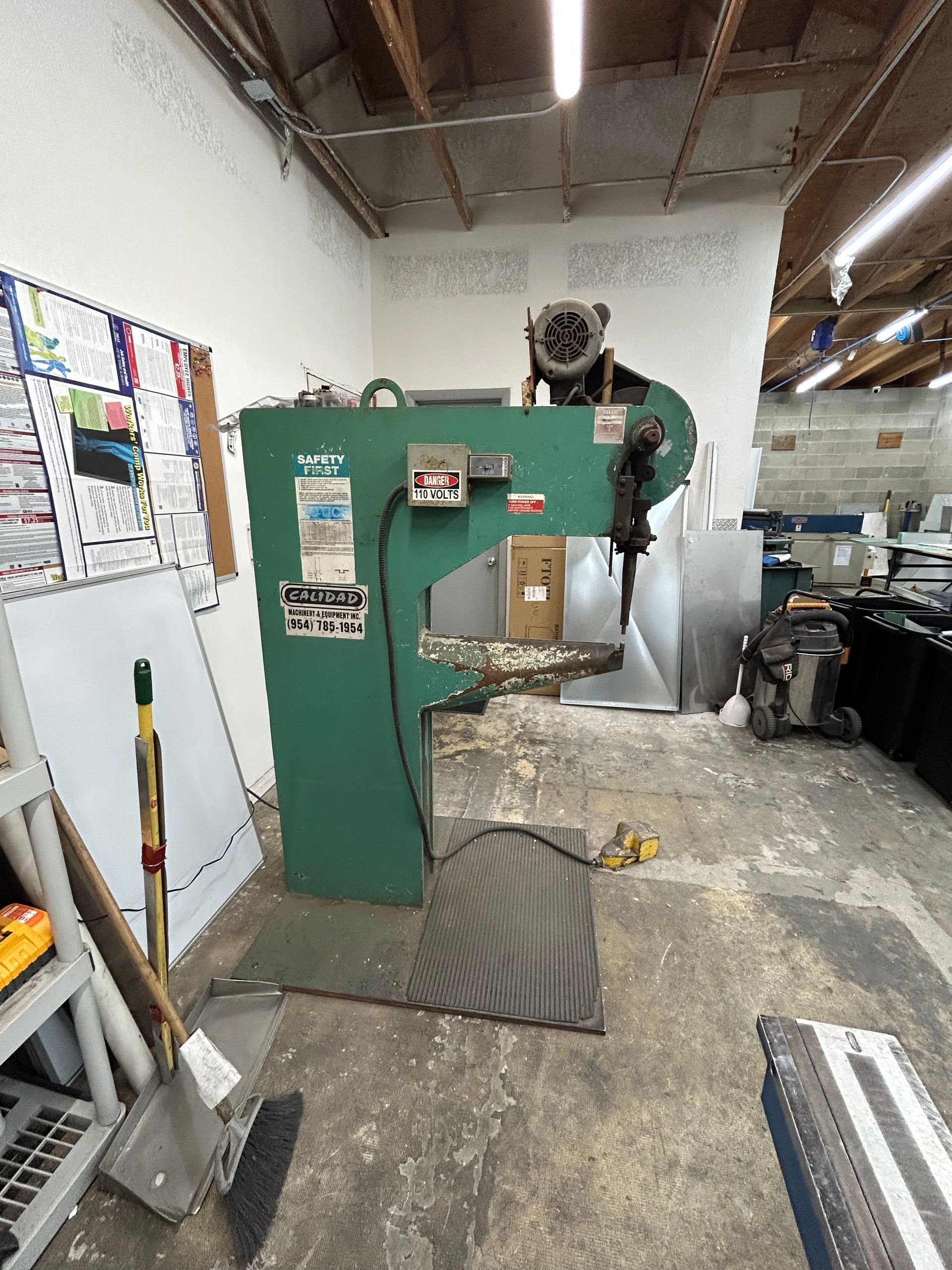 Green industrial punch press in a workshop setting.