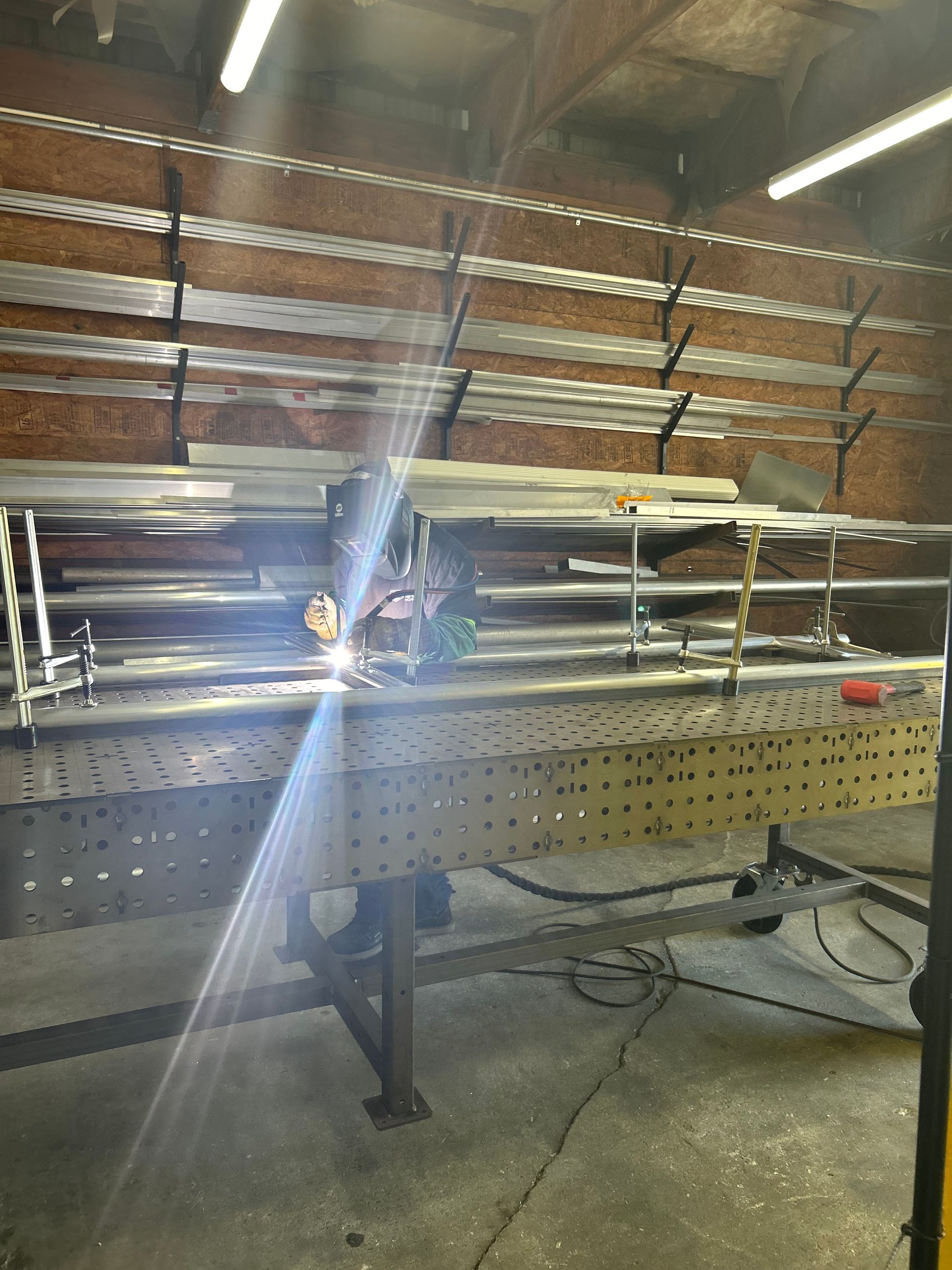 Person welding metal on a table in a workshop, bright sparks flying.