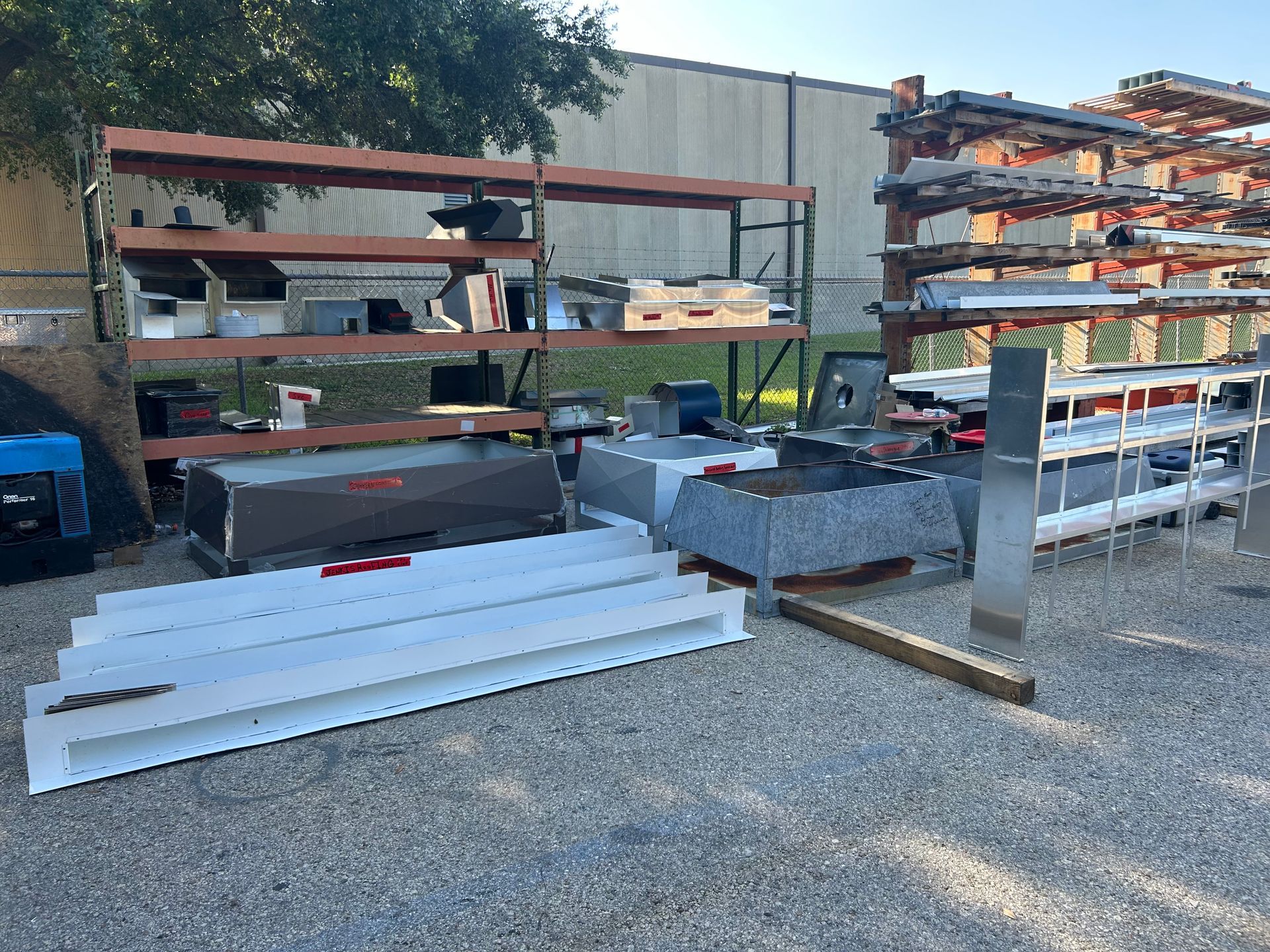 Outdoor storage area with shelves and various metal parts.