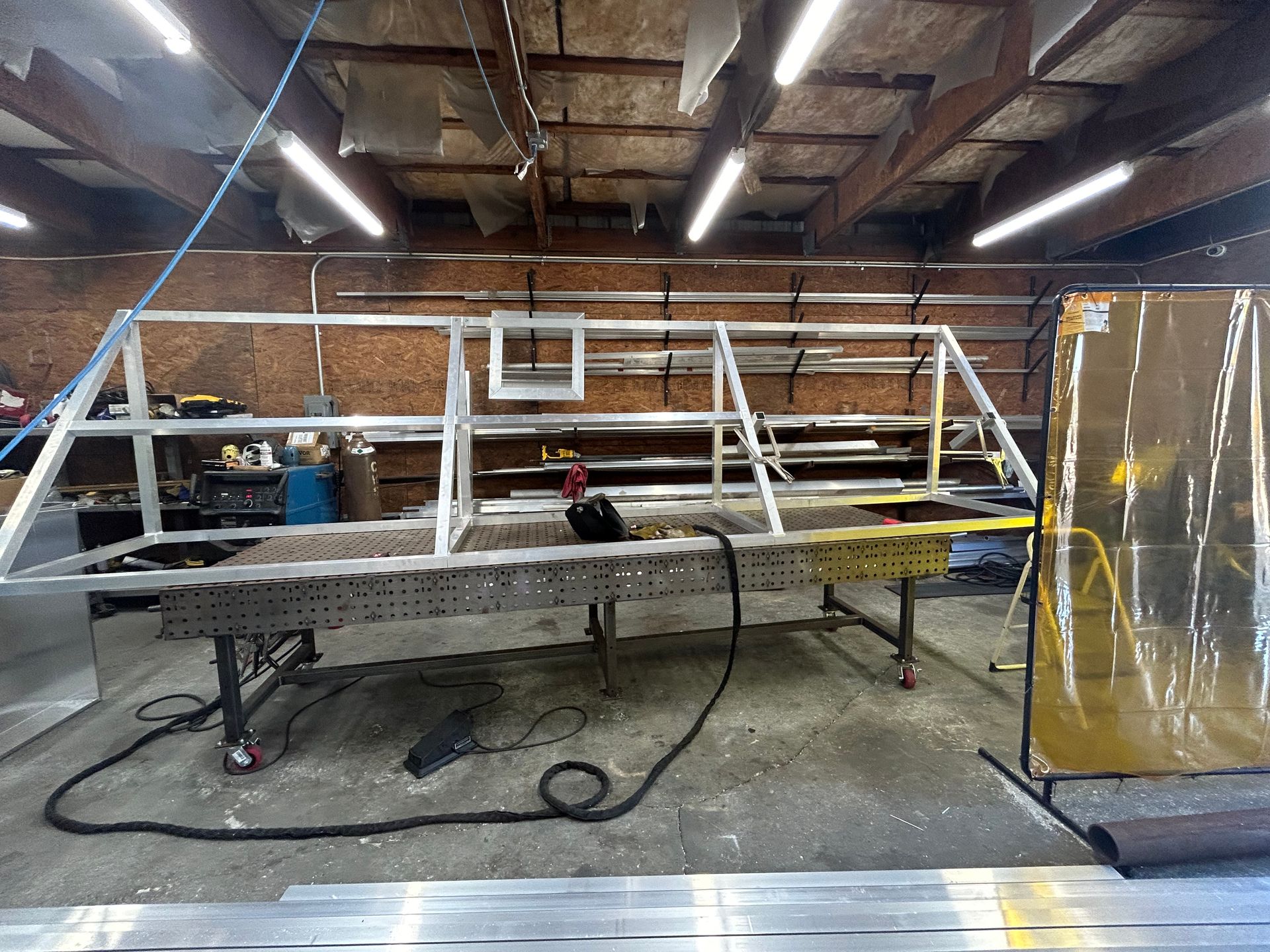 A metal frame being welded on a workbench inside a workshop.