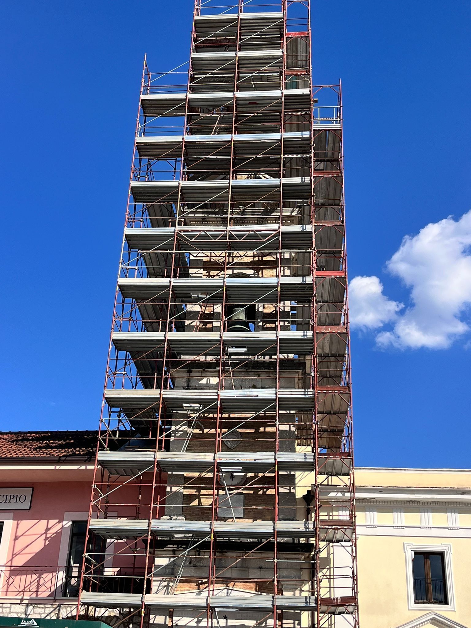 Un'impalcatura ricopre un alto edificio in costruzione, sullo sfondo di un cielo azzurro e terso.