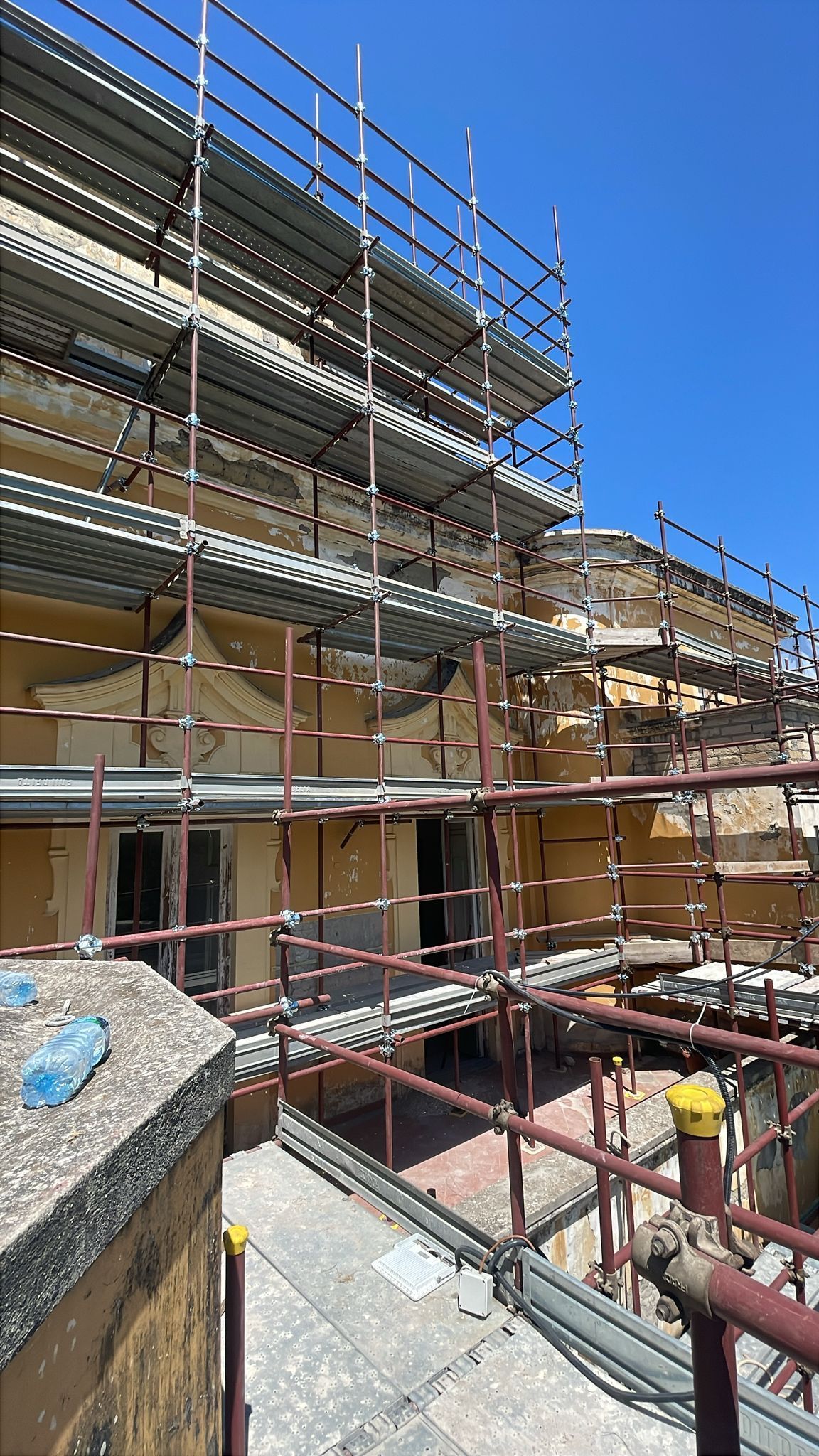 Esterno di un edificio in costruzione, con impalcature. Giornata di sole, cielo azzurro.