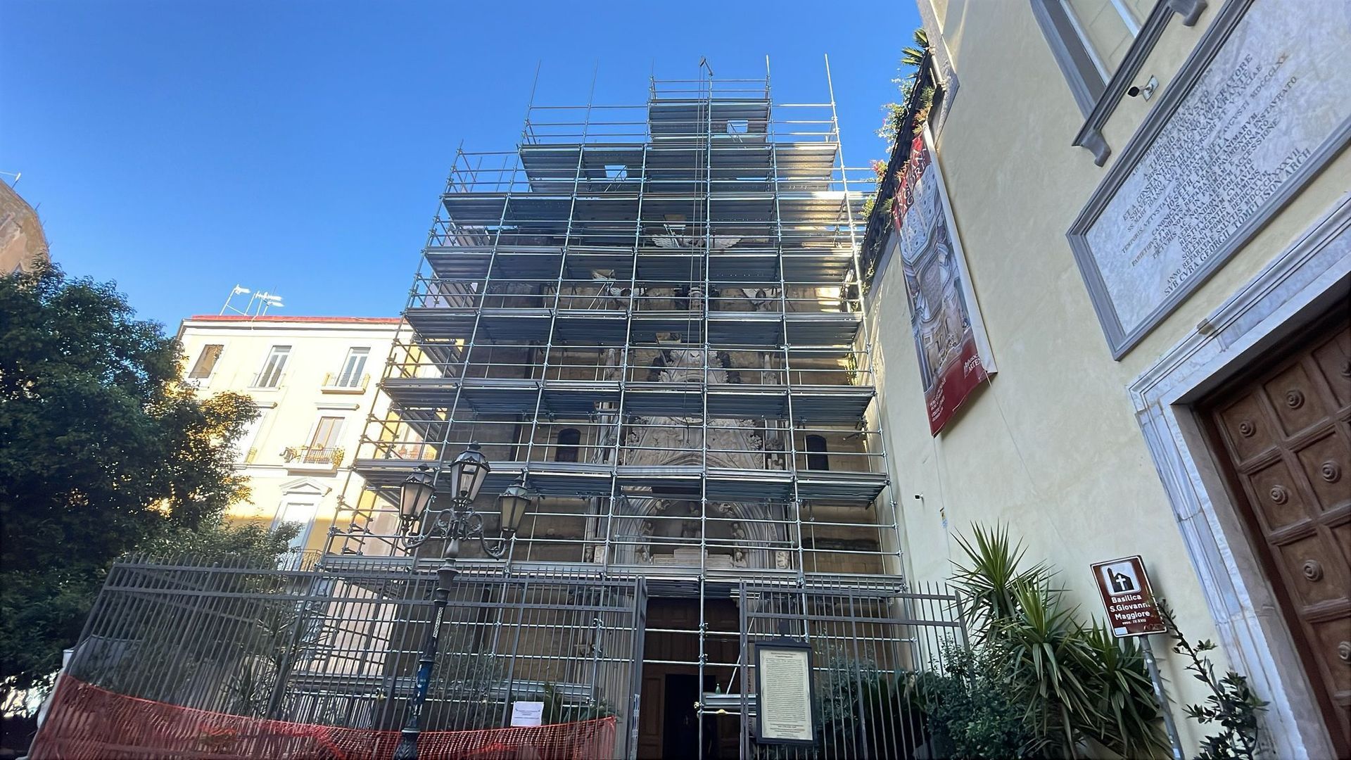 Edificio in ristrutturazione, coperto da impalcature, contro un cielo azzurro e terso.