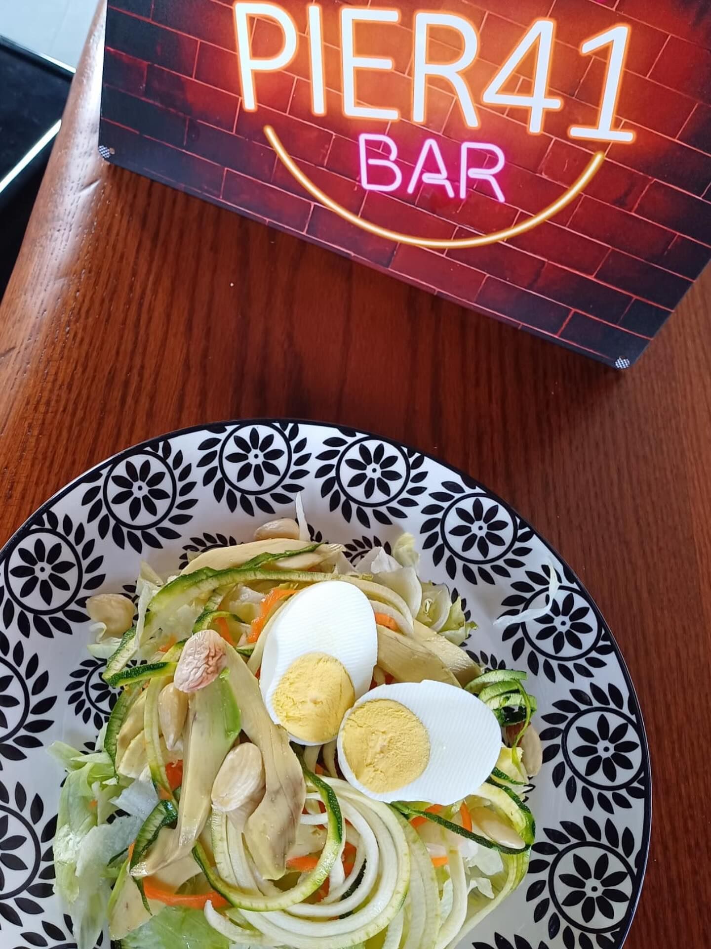 Insalata con uova sode su un piatto decorato accanto a un'insegna al neon con la scritta