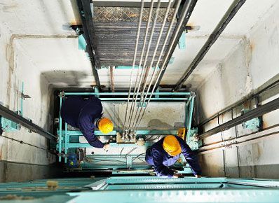 Dos hombres están trabajando en un ascensor en un edificio.