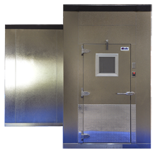 A walk-in cooler with a metal door, small window, and stainless steel panels.