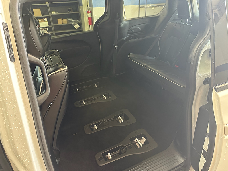 Empty interior of a white minivan with black seats and floor tracks, likely for wheelchair access. | The Garage Automotive Solutions
