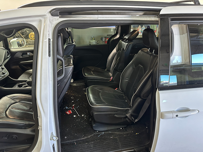 White minivan interior with opened sliding door, black leather seats, and debris on floor. | The Garage Automotive Solutions