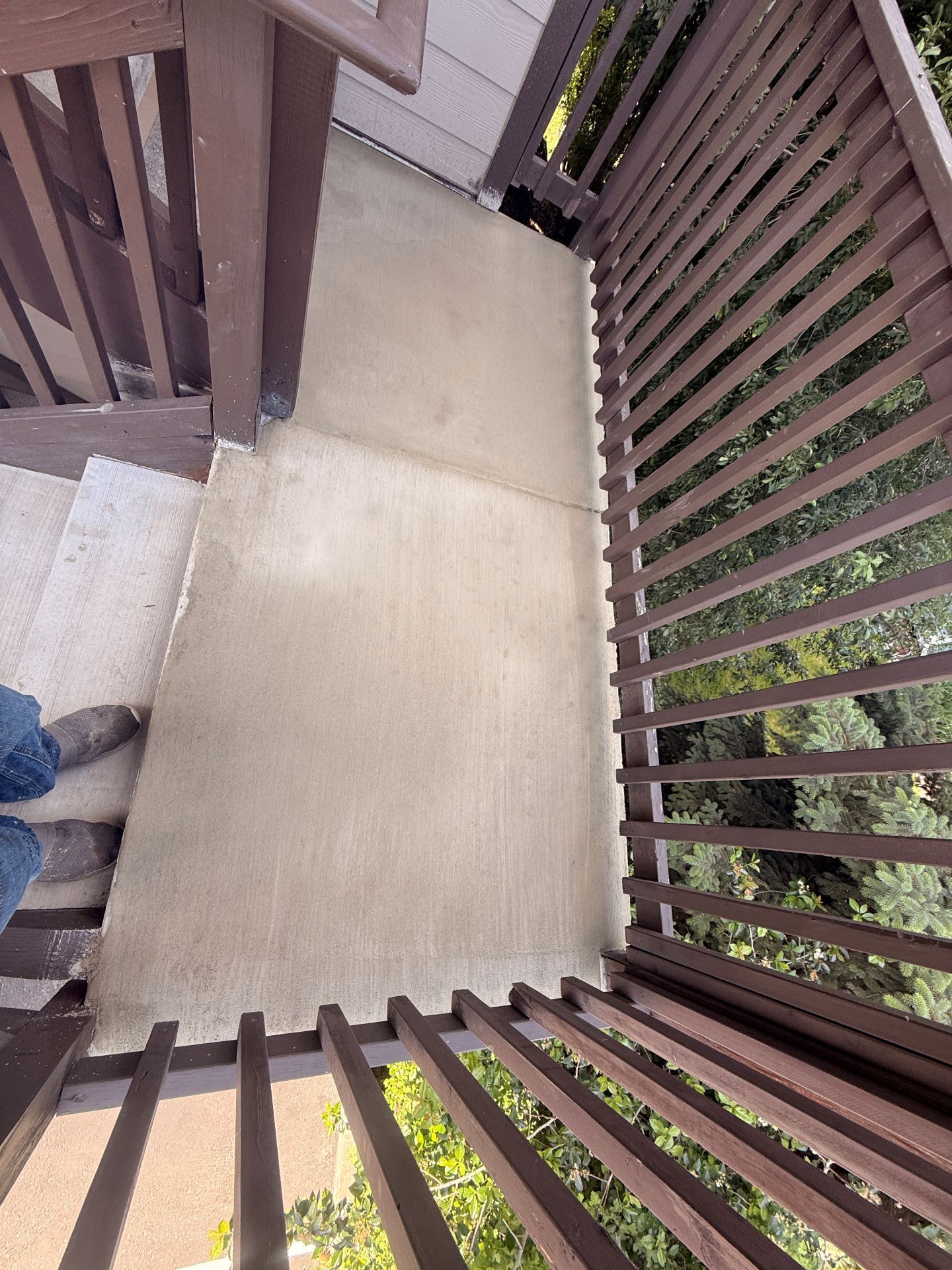 Wooden balcony or stair landing with beige floorboards and railing, viewed from above.