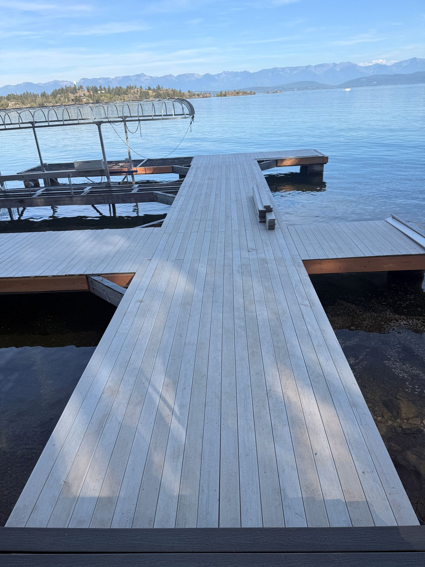Wooden dock extending into a calm blue lake with mountains in the distance