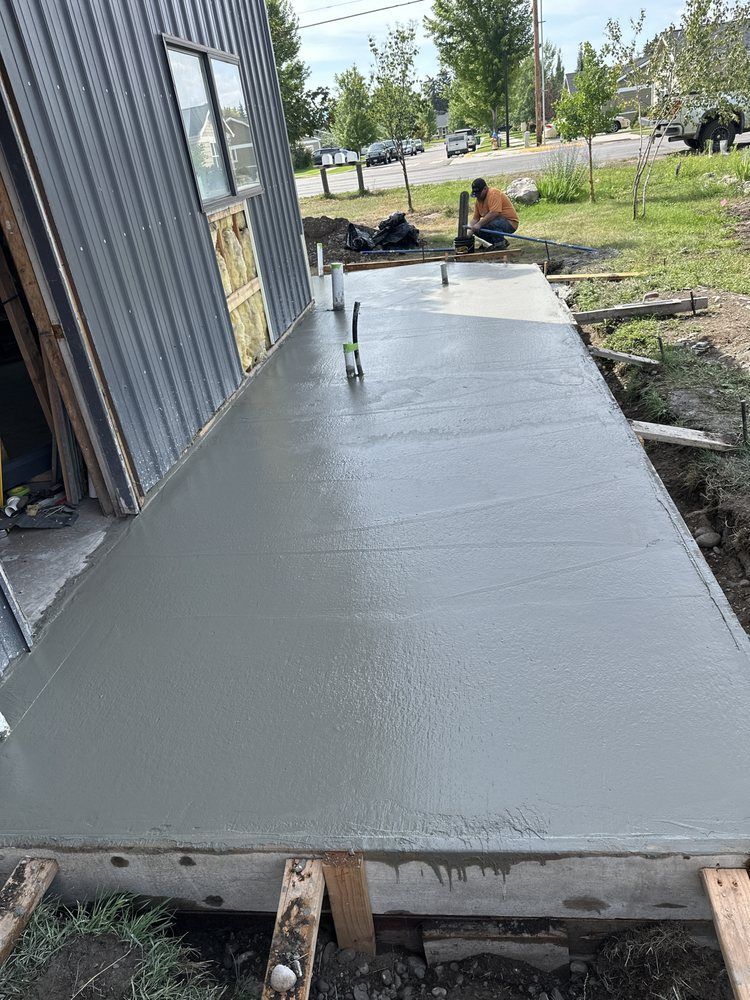 Freshly poured concrete ramp beside a building, with a worker in the background