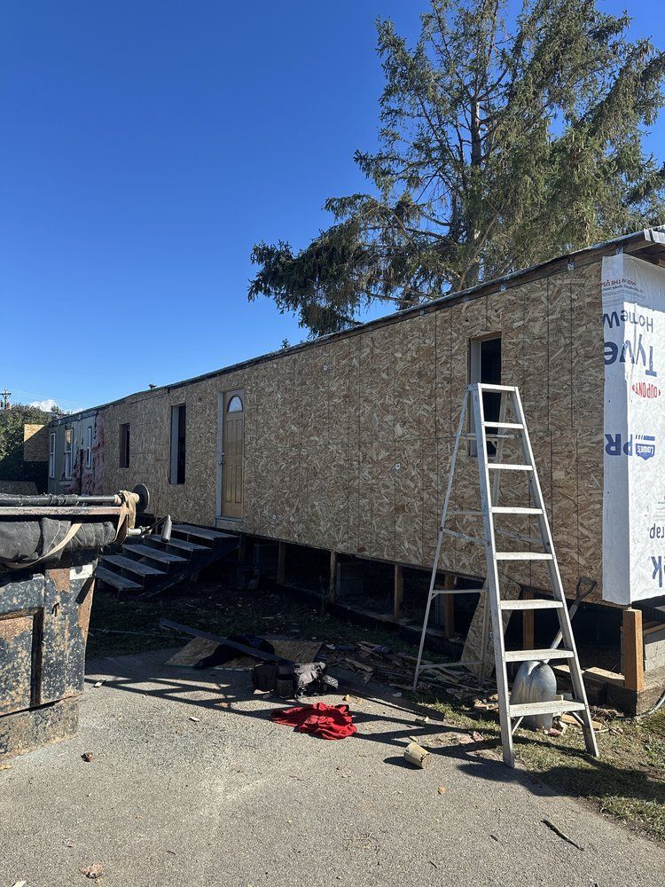 Mobile office trailer under construction with ladder and tools outside on a sunny day