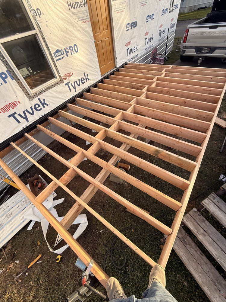 Partially framed roof over a house under construction, with Tyvek-wrapped walls and exposed rafters.