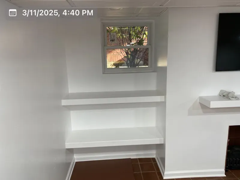 Built-in white shelves in a recessed wall, below a window.  A white floating shelf beside a fireplace.