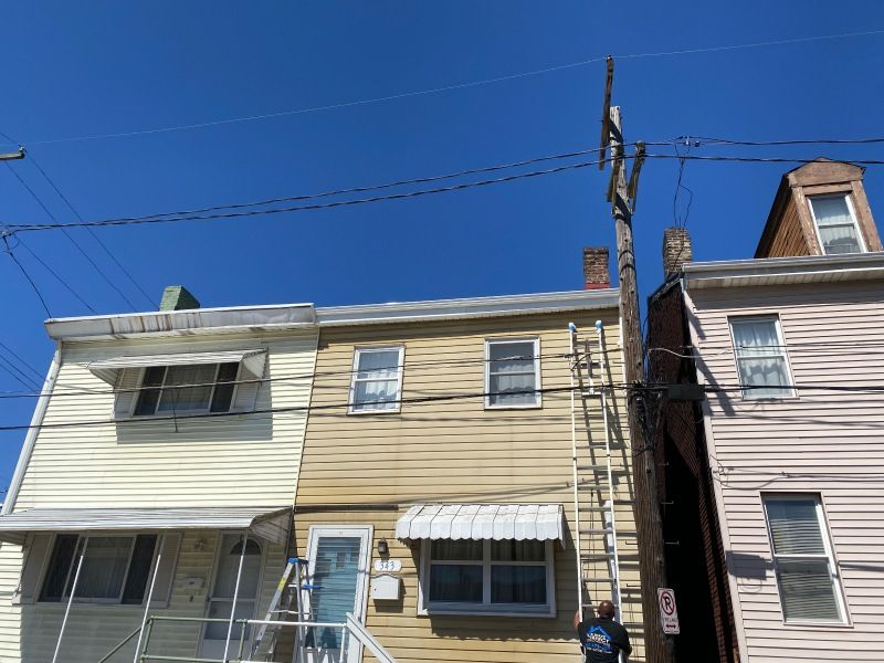 Row houses with a utility pole and ladder on sunny day; blue sky.