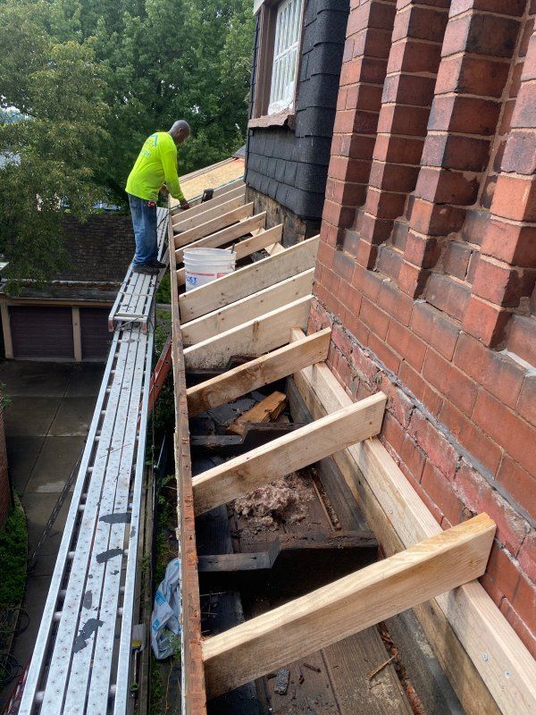 Construction worker on scaffold repairing roof near brick chimney.