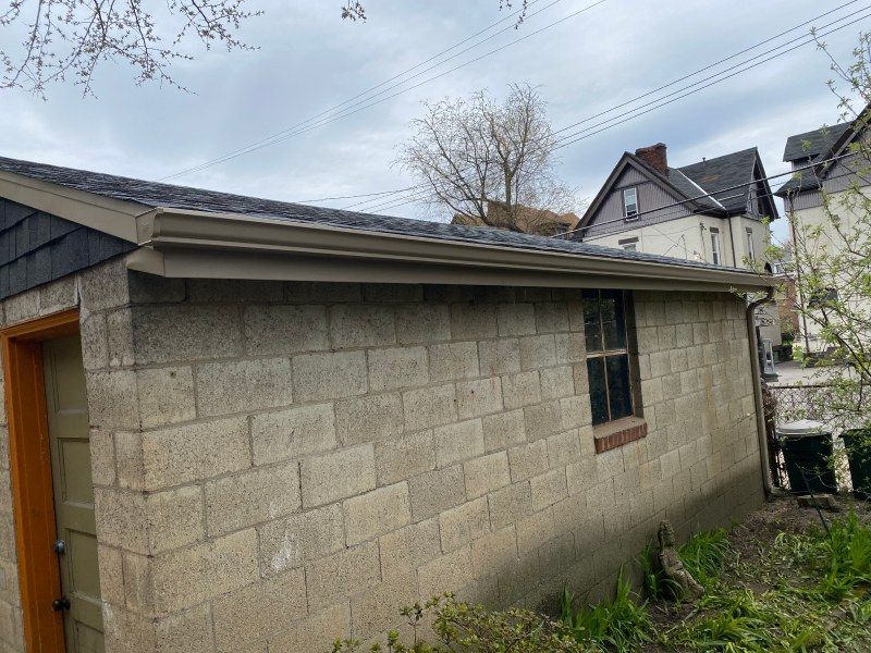 Garage with cinder block walls, brown trim, and a window. Overcast sky in the background.