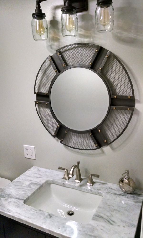 Bathroom with industrial-style mirror, light fixture, marble countertop, and sink.
