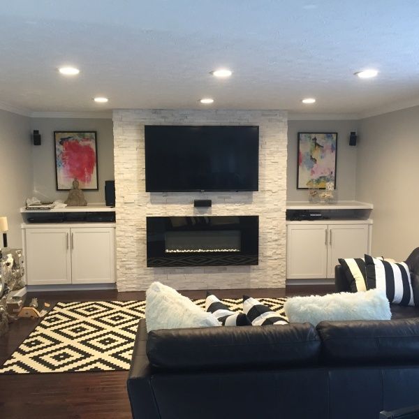 Living room with fireplace, TV, and artwork on a white stone accent wall.