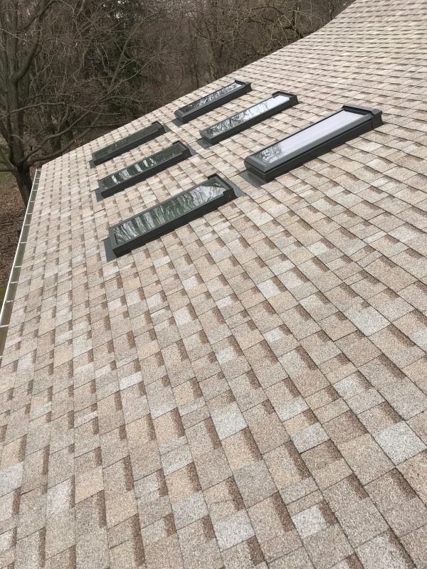 Roof with six rectangular skylights; tan shingles.