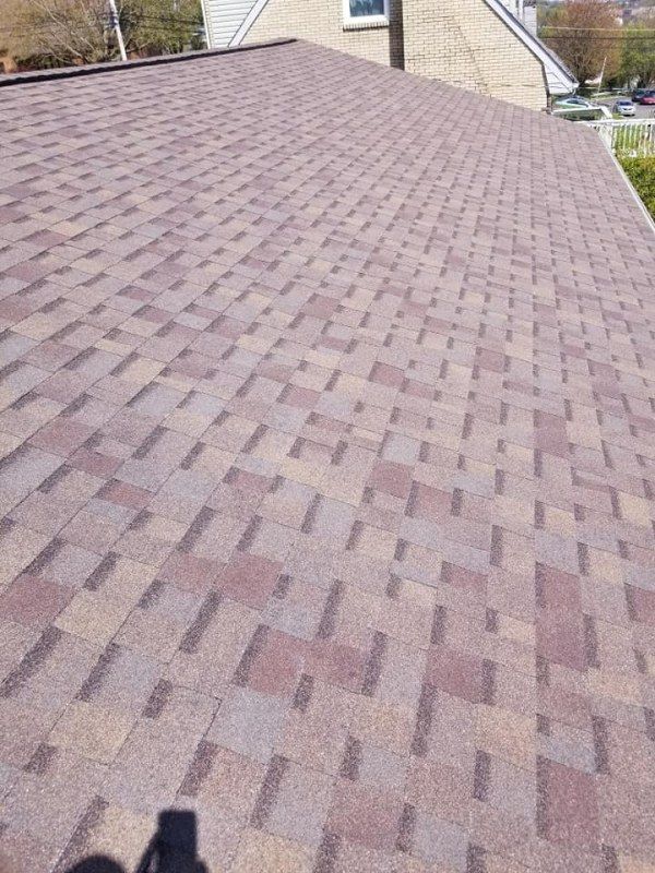 Brown and tan asphalt shingle roof on a house, angled view.
