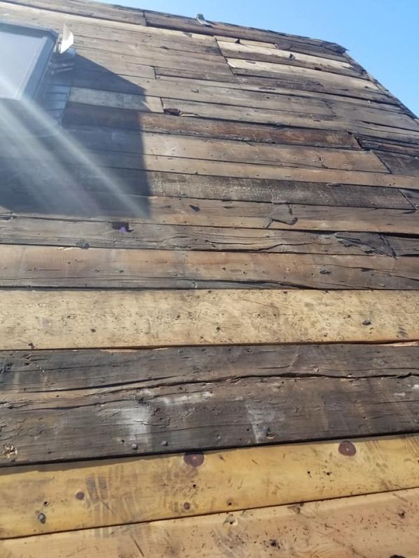 Close-up of a weathered wooden roof with a small window, showing horizontal planks in shades of brown and gray.