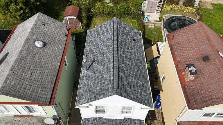 Overhead view of three houses with gray roofs. One is white, one is green, and one is tan.