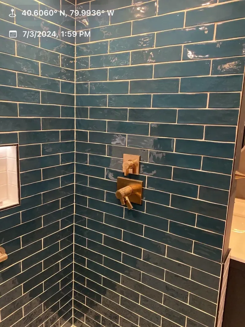 Blue tile shower interior with gold fixtures.
