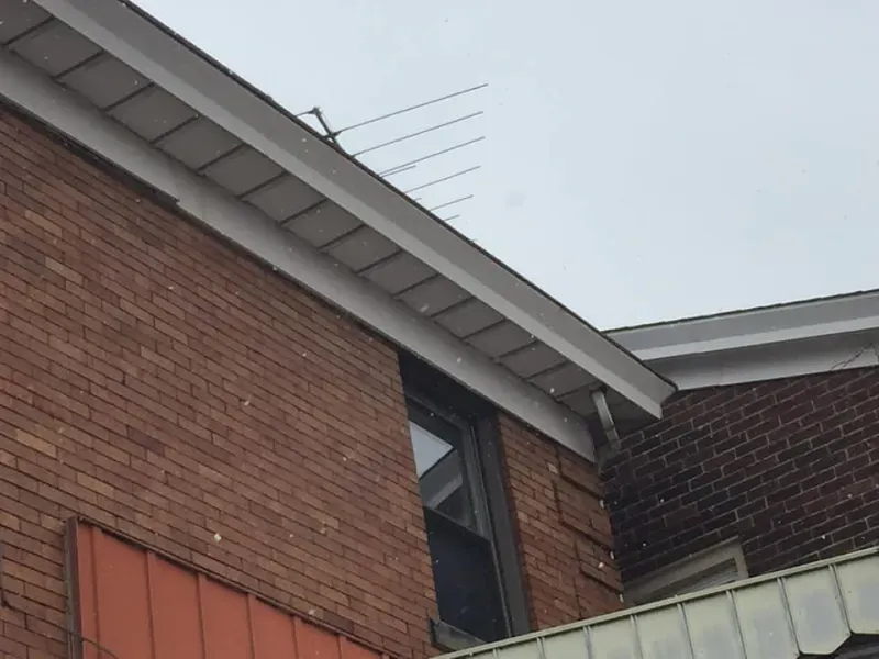 Brick building with white trim, a window, and an antenna on the roof.