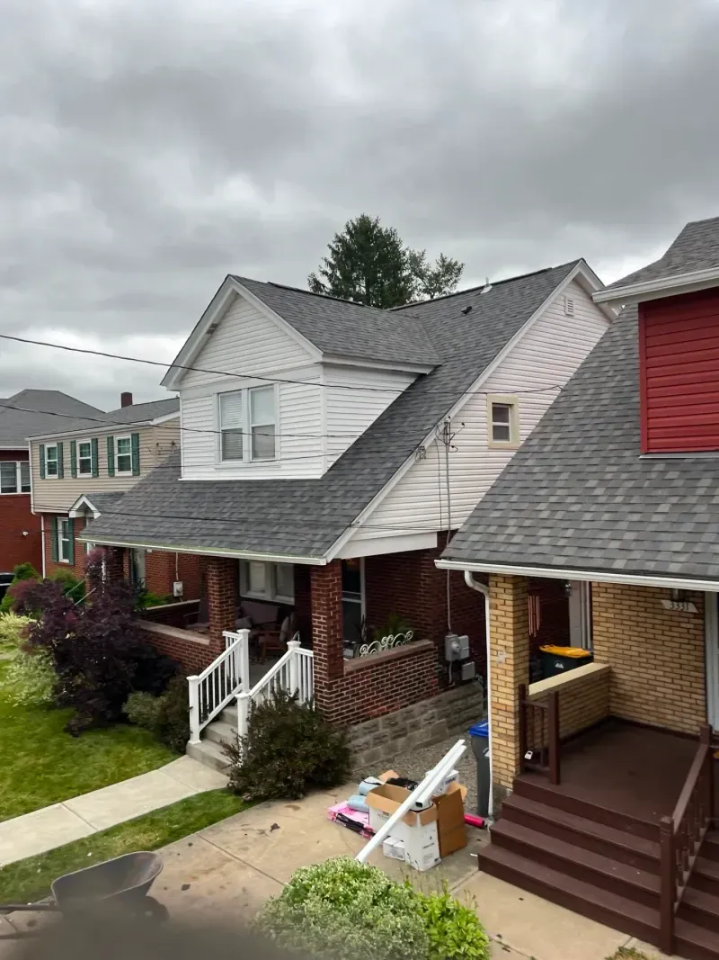 Houses with gray roofs, red brick, and white trim on a cloudy day.