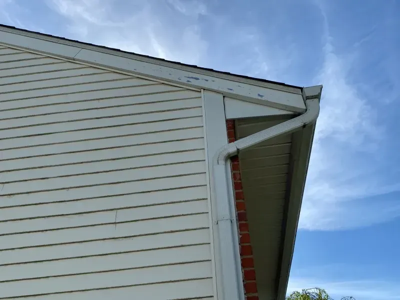 White house siding and gutters under a blue sky.