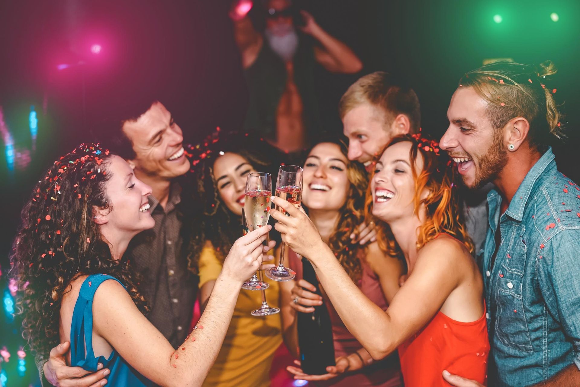 Group of people toasting champagne in a brightly lit room, celebrating.