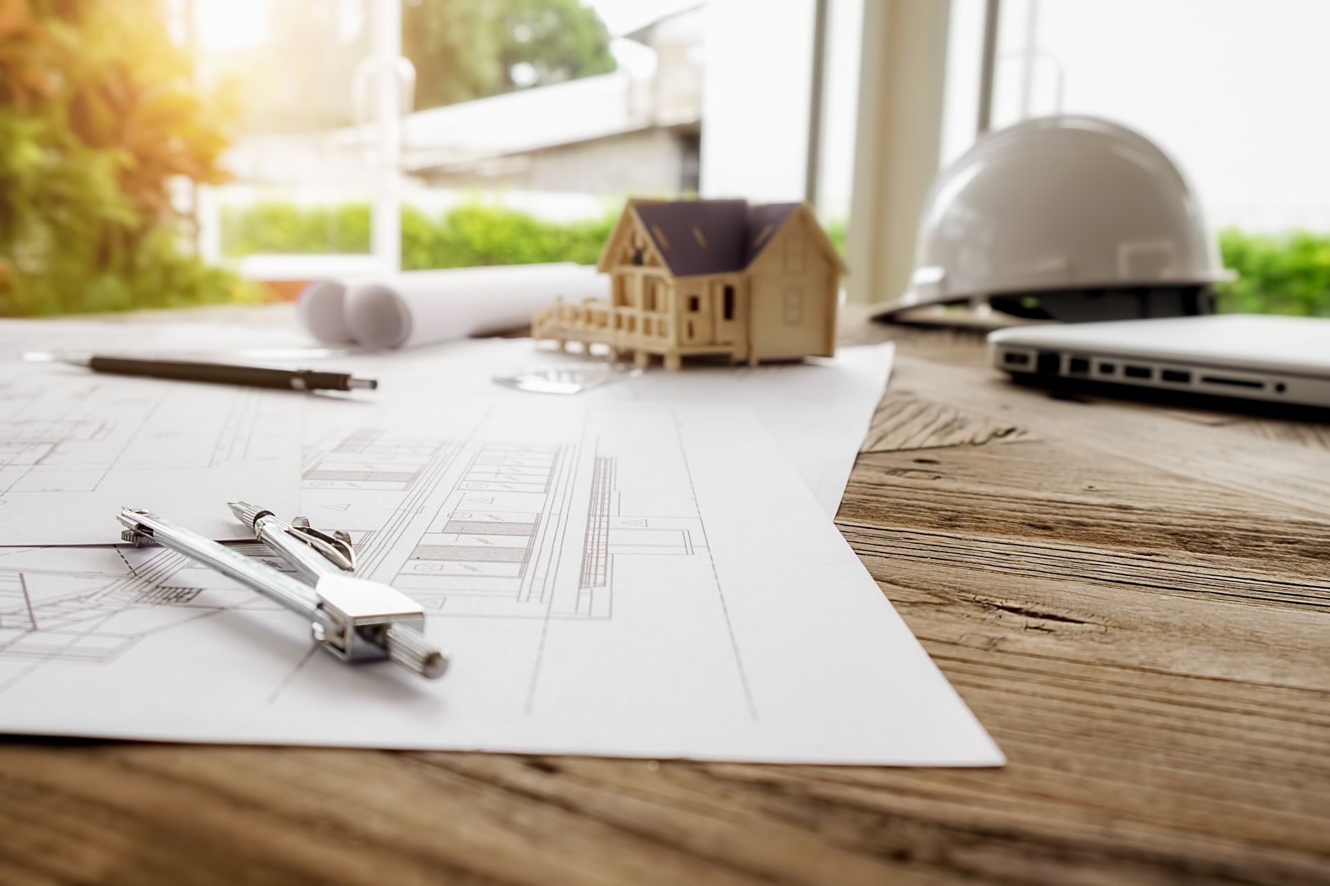 A wooden table with a compass , pen , and a model house on it.