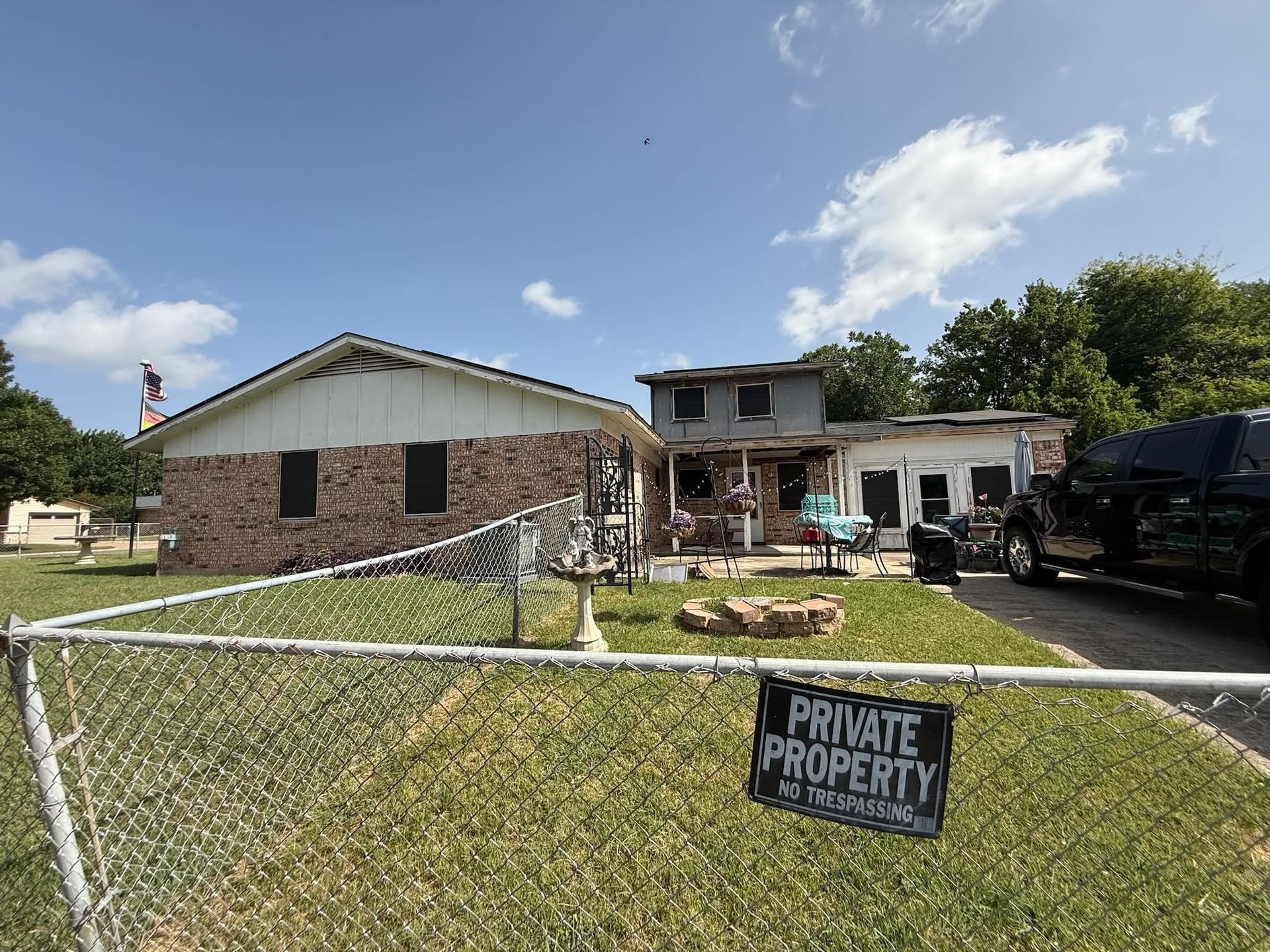 Brick house with white garage, chain-link fence, and “Private Property” sign in front yard