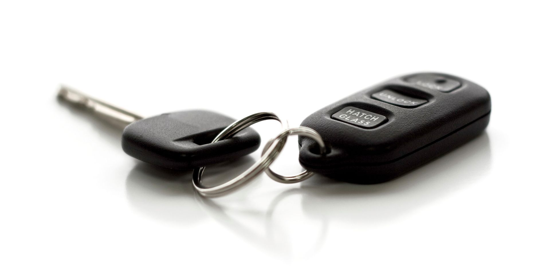 A pair of car keys sitting on top of each other on a white surface. A pair of car keys sitting on top of each other on a white surface.