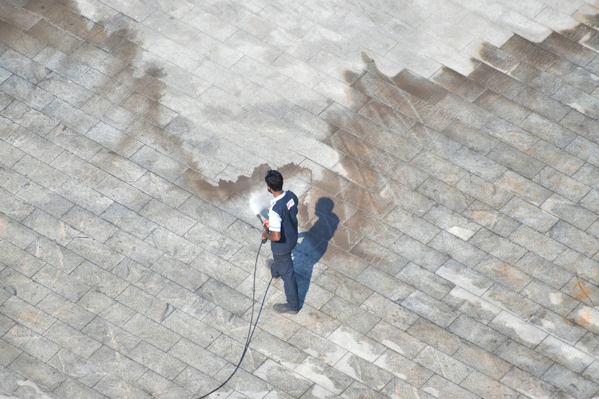 Worker pressure washing a large tiled roof to remove dirt and surface buildup. Worker pressure washing a large tiled roof to remove dirt and surface buildup.