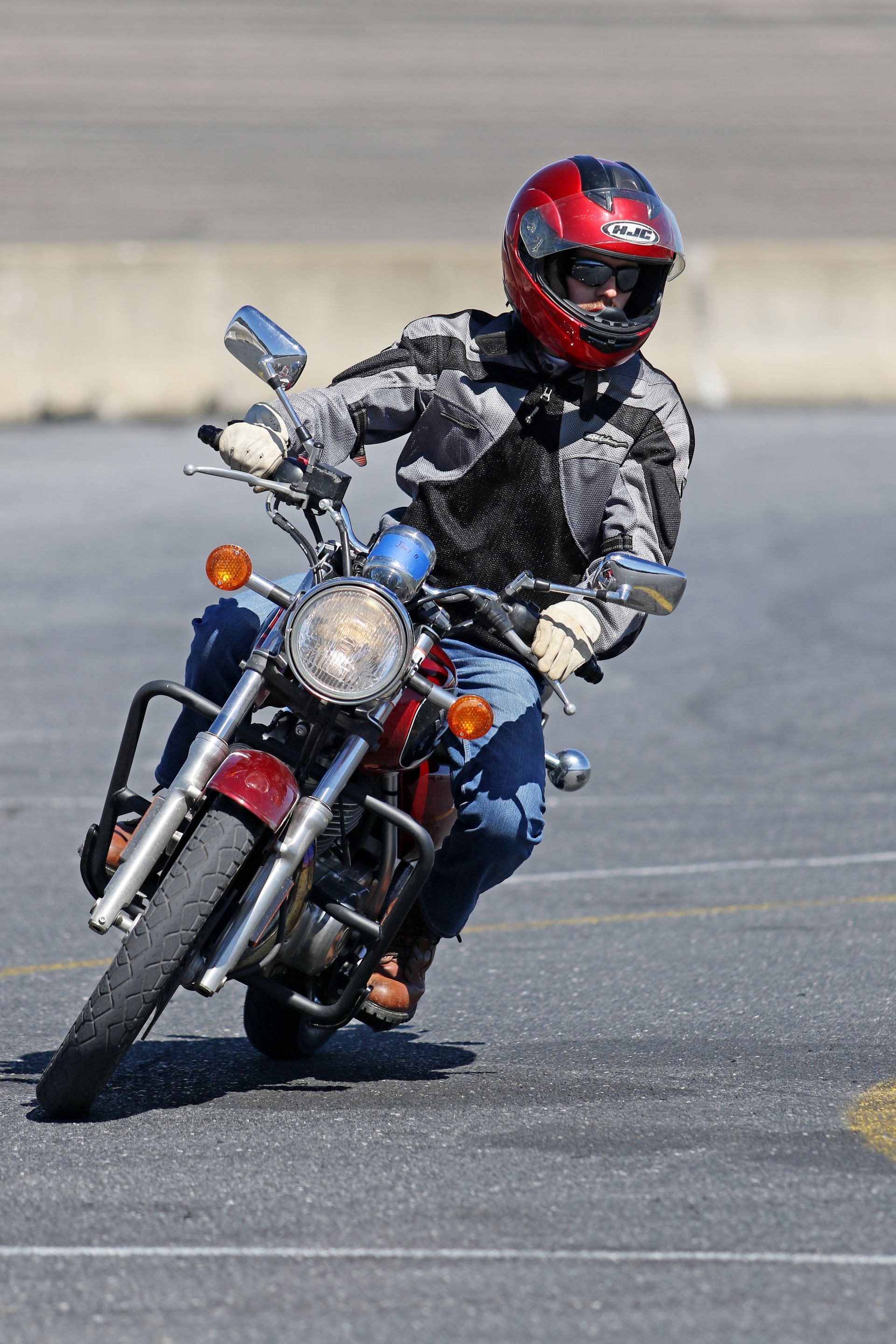 A man wearing a red helmet is riding a motorcycle on a road