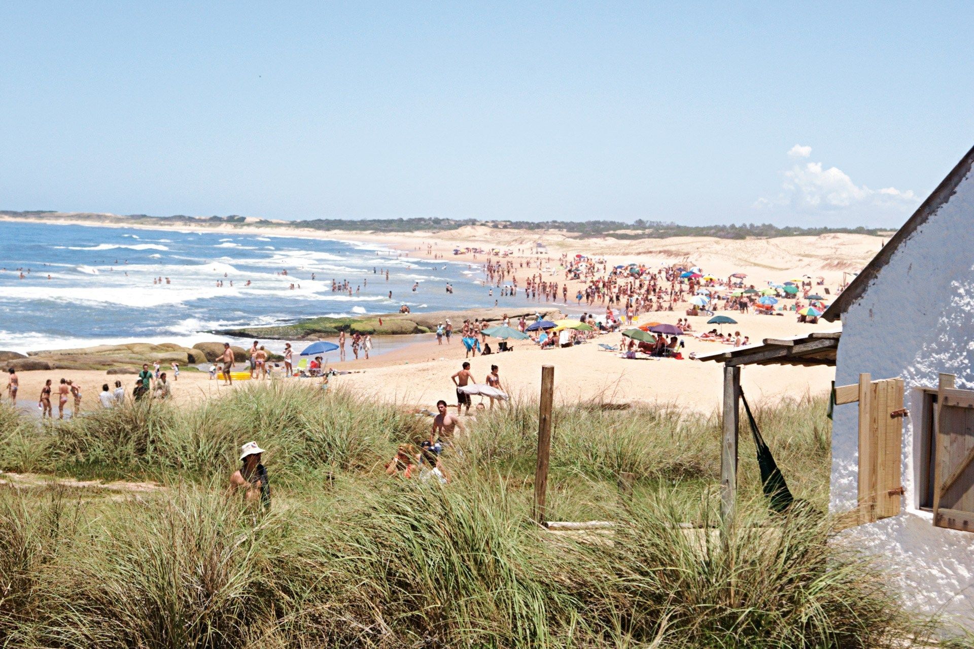 A view of a beach with a white house in the foreground