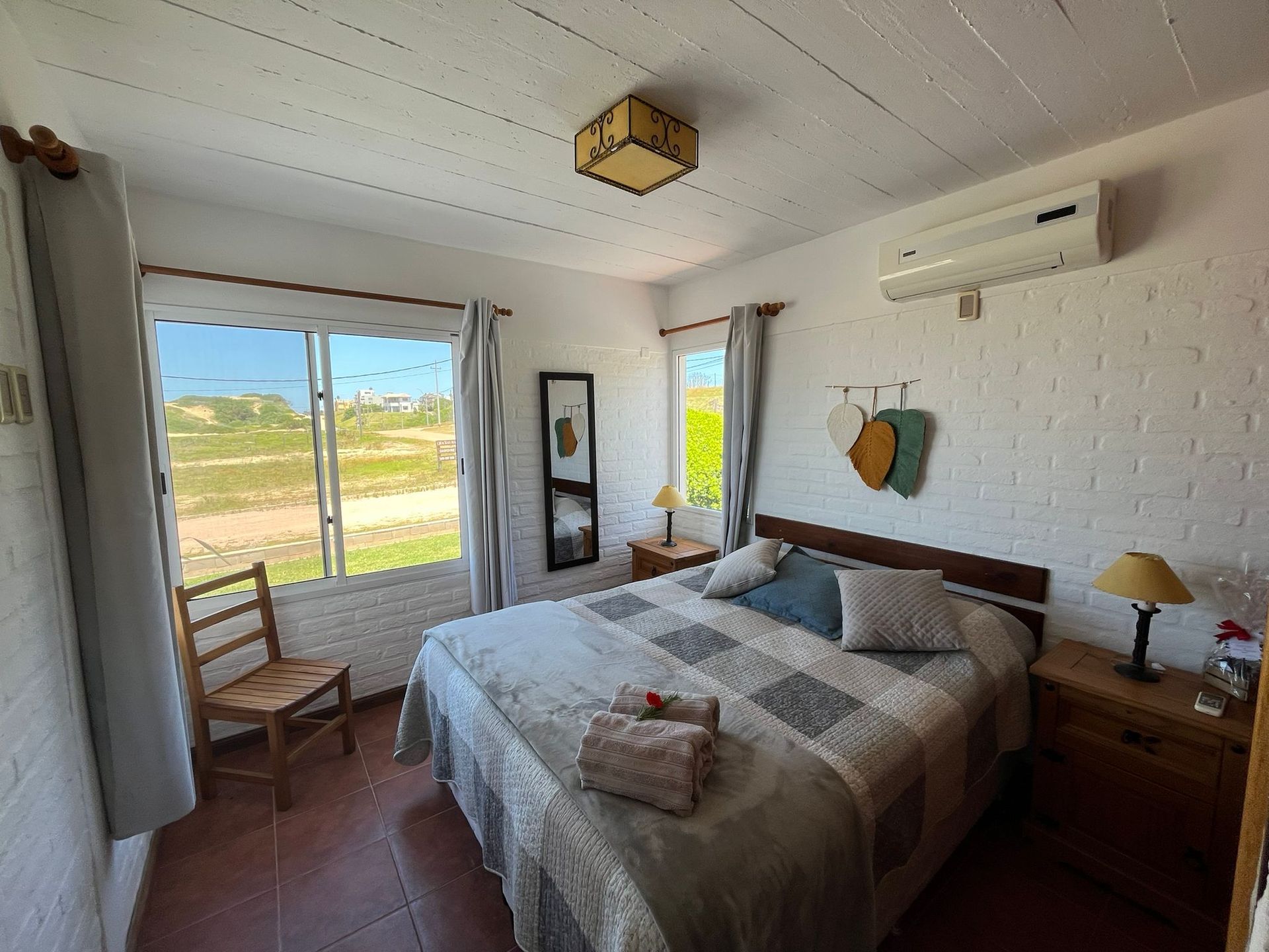 A bedroom with a bed , chair , nightstand and window.