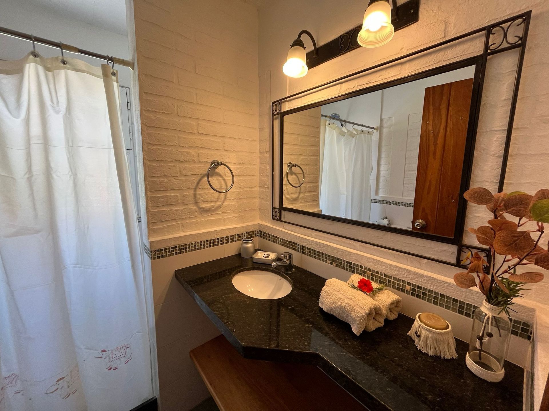A bathroom with a sink , mirror and shower curtain.
