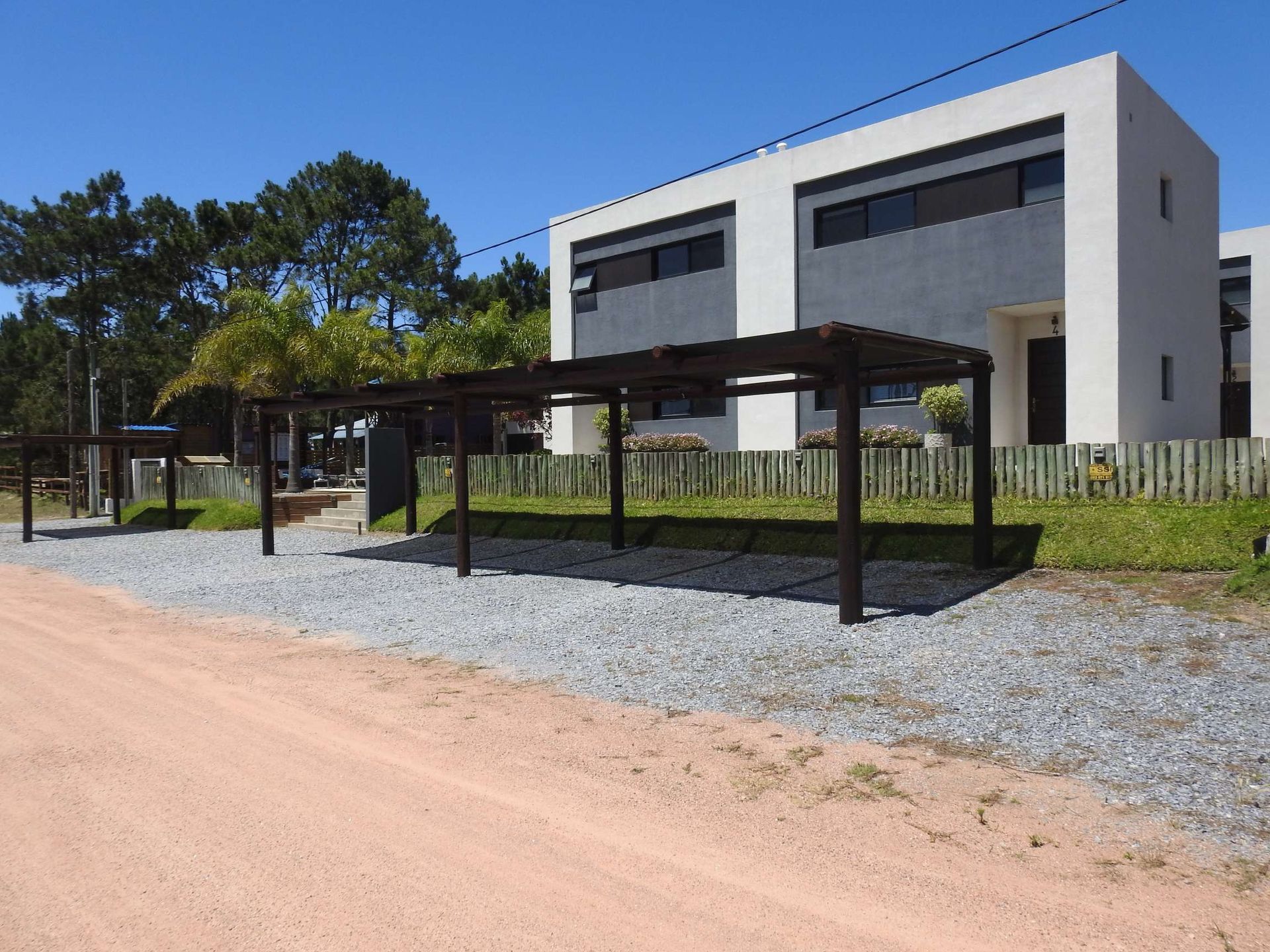 A white building with a wooden pergola in front of it