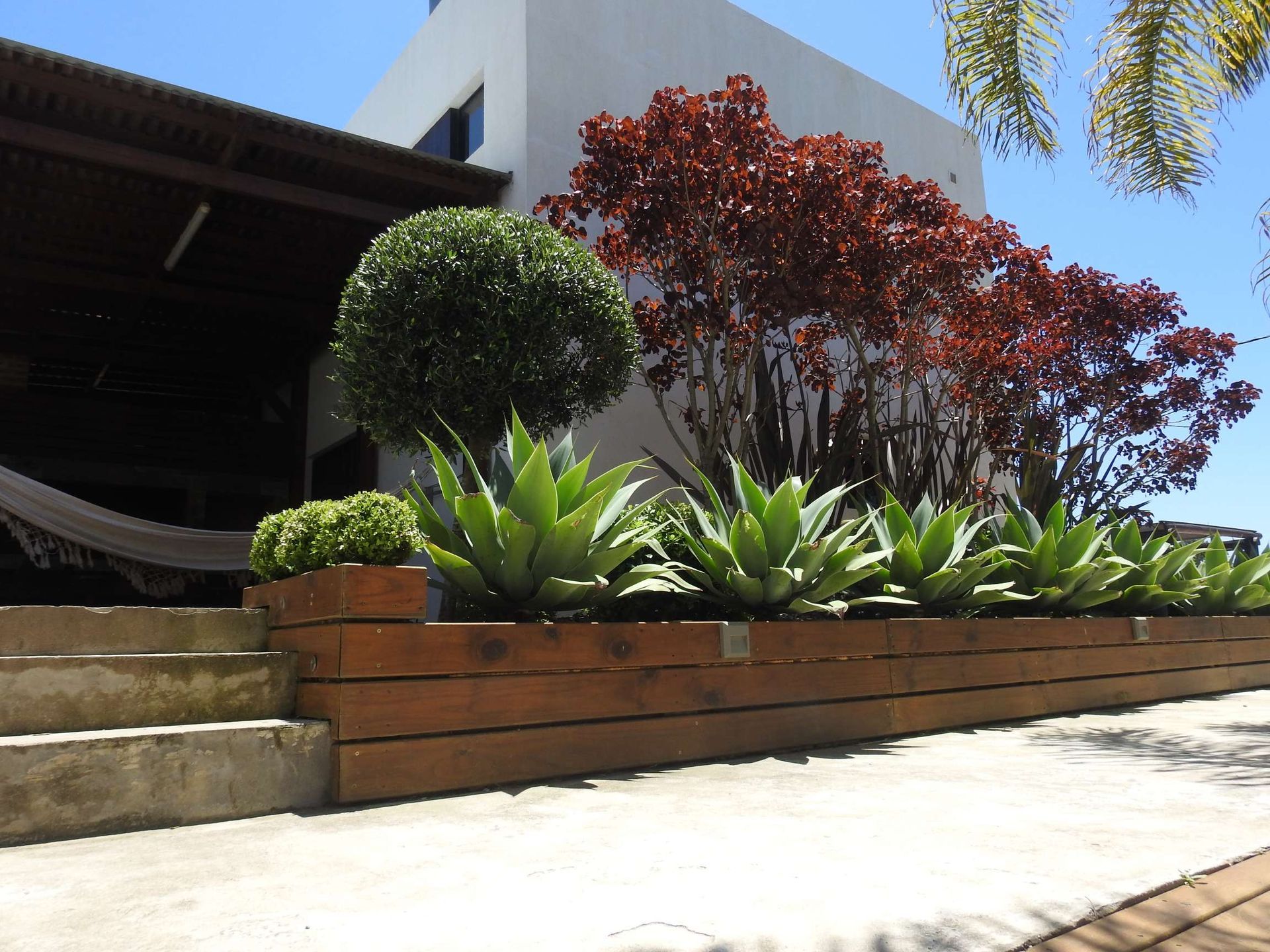 A house with a hammock and plants in front of it