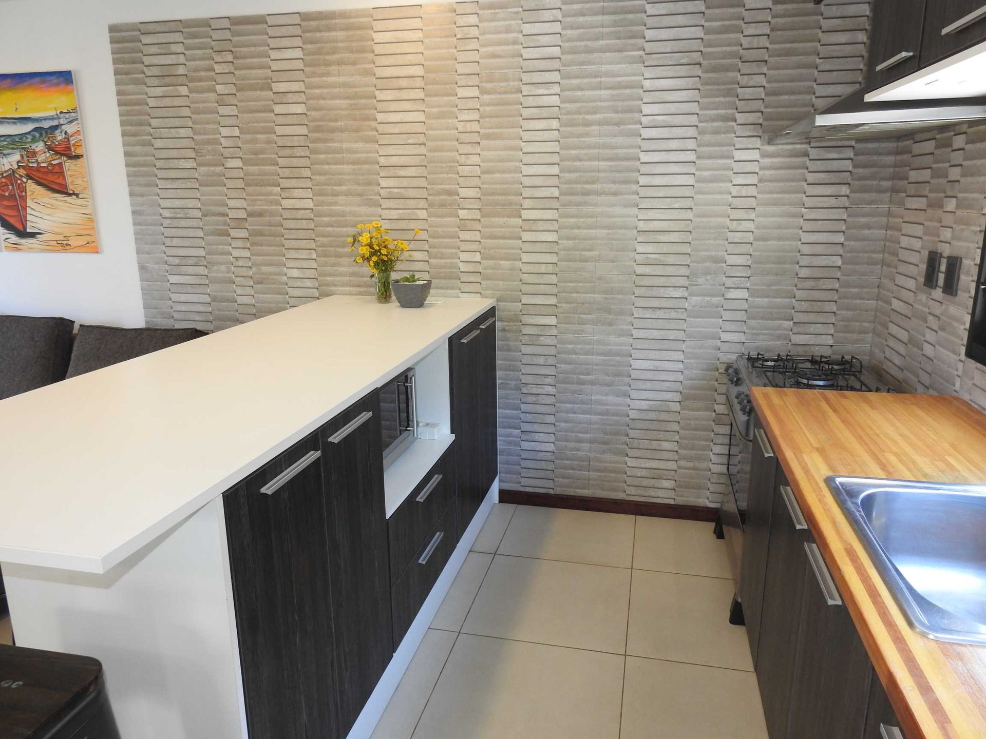 A kitchen with a painting on the wall above the sink