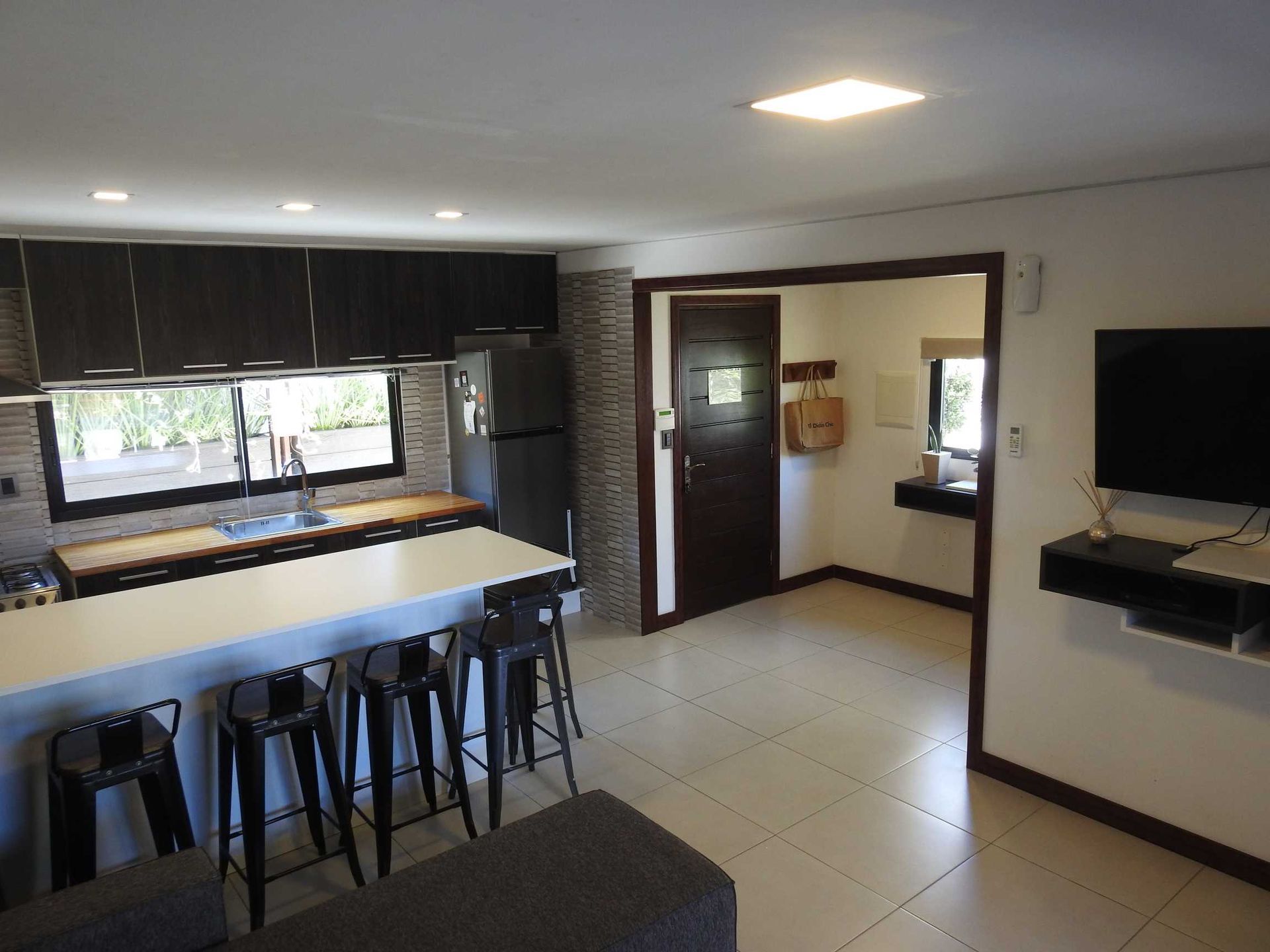A living room with a kitchen and a flat screen tv